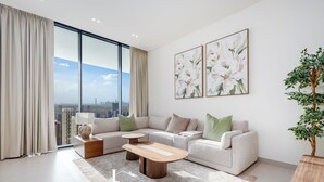 A modern living room with a large window, a sofa set, a coffee table, and a potted plant. - LUX  The Phantom Sky Pool Suite (Dubai)