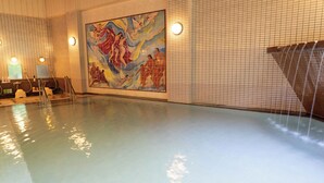 Uima-allas, jonka seinillä on seinämaalaus, ja jossa on laatoitetut seinät sekä koristeellinen vesielementti.