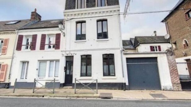 Un bâtiment à deux étages doté d’une porte de garage et d’un petit porche.