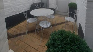 A small courtyard with a round table and four chairs, surrounded by white brick walls. - Magnificent house ideally located in st Valery sur somme (Saint-Valery-sur-Somme)