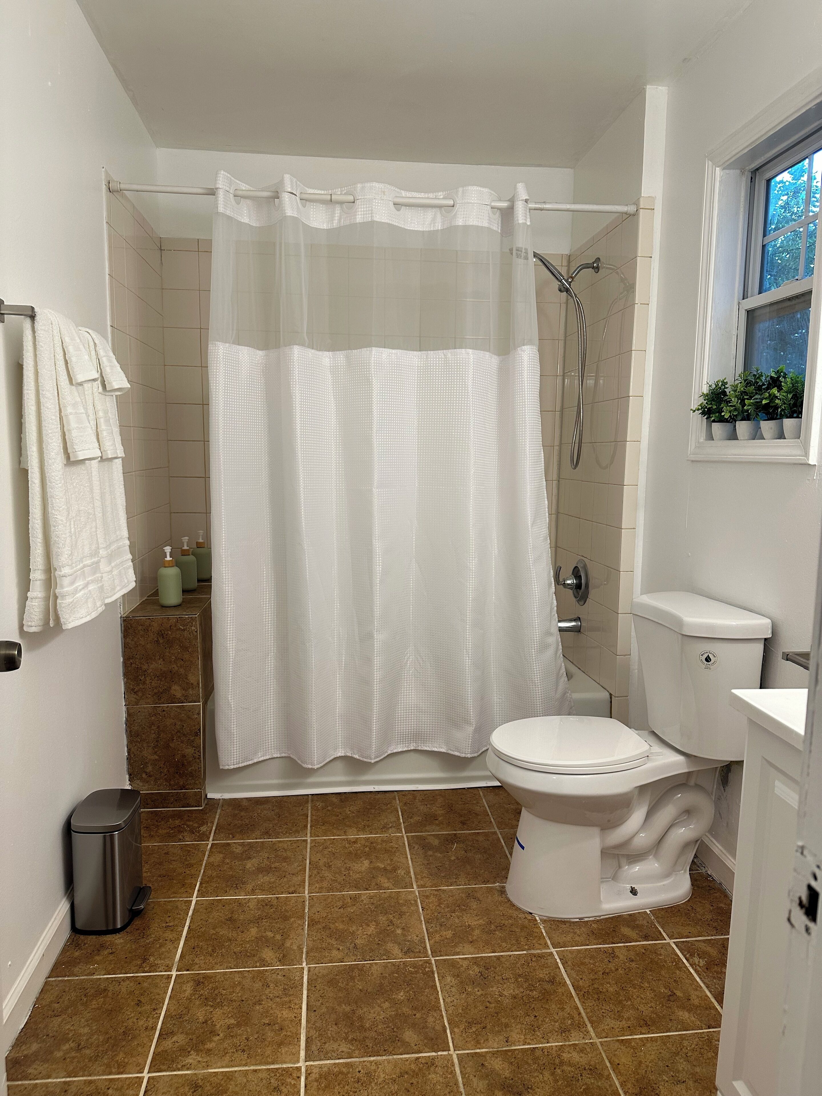 Une salle de bain avec douche, toilettes et lavabo.