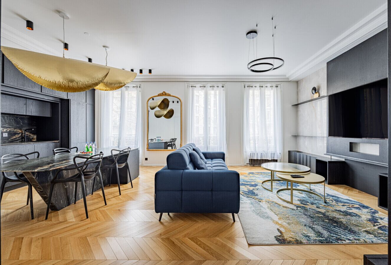 Ein modernes Wohnzimmer mit einer Couch, einem Esstisch, Stühlen und einem Fernseher.