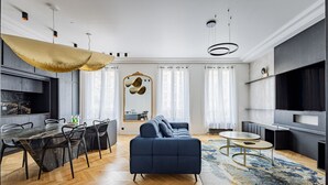 A modern living room with a sofa, dining table, chairs, and a TV. - Avenue Niel - Place des Ternes - 2 chambres - Luxe (Paris)