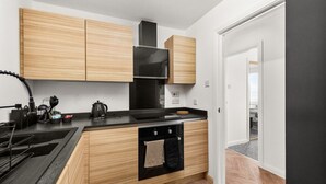 A modern kitchen with wooden cabinets, a black countertop, a built-in oven, and a microwave. - Ochil View 30 mins to Edinburgh (Falkirk)