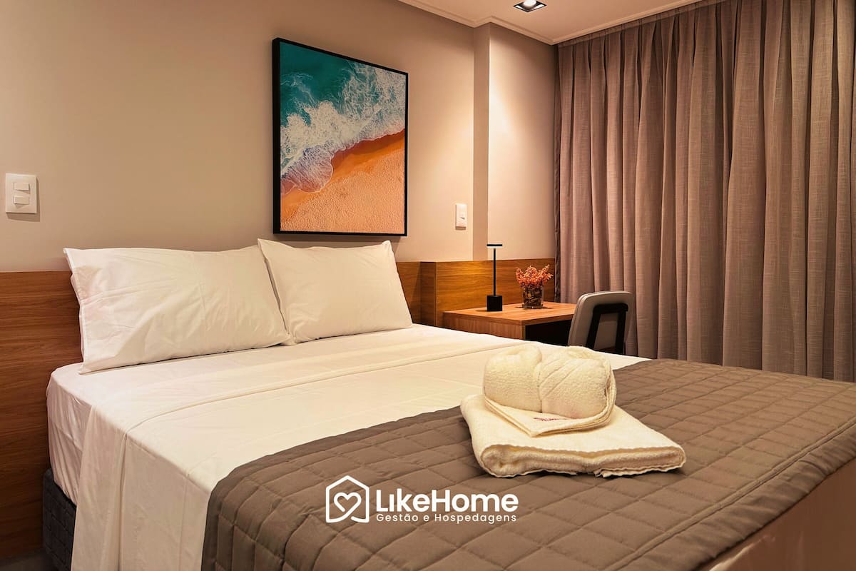 Une chambre d’hôtel avec un lit, un tableau représentant une plage, un bureau et une chaise.