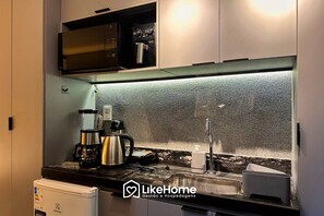 Une cuisine moderne équipée d’un four à micro-ondes, d’une machine à café, d’une bouilloire et d’un évier.