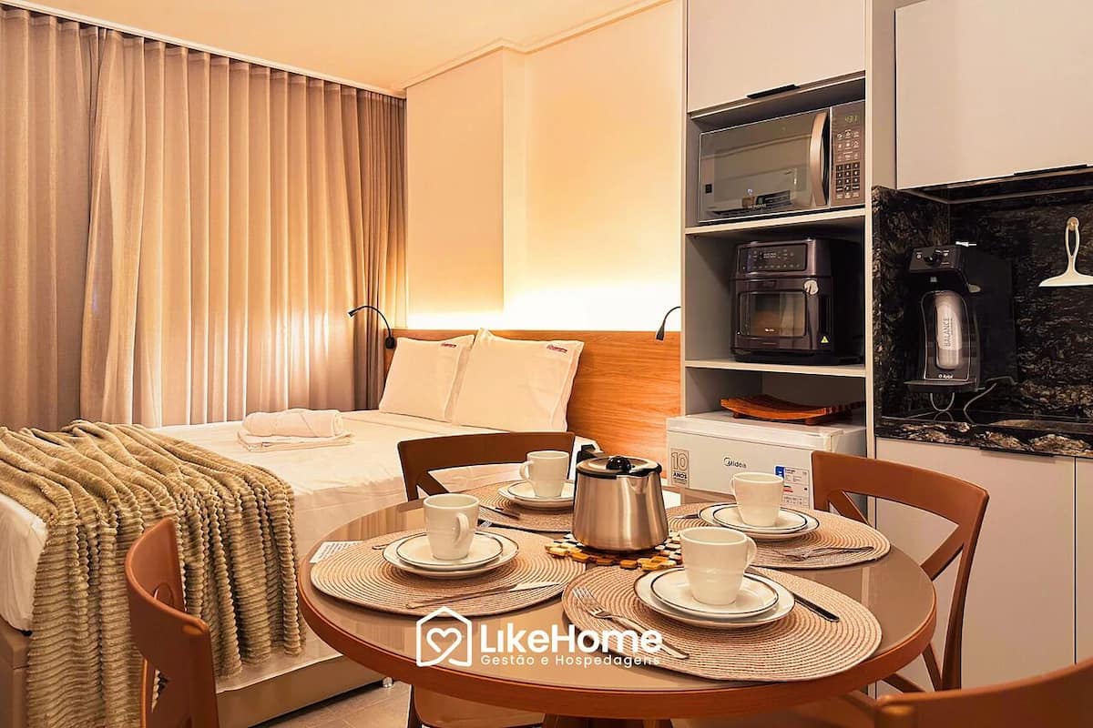 Une chambre d’hôtel équipée d’un lit, d’une table à manger avec des tasses et une cafetière, d’un four à micro-ondes et d’une machine à café.
