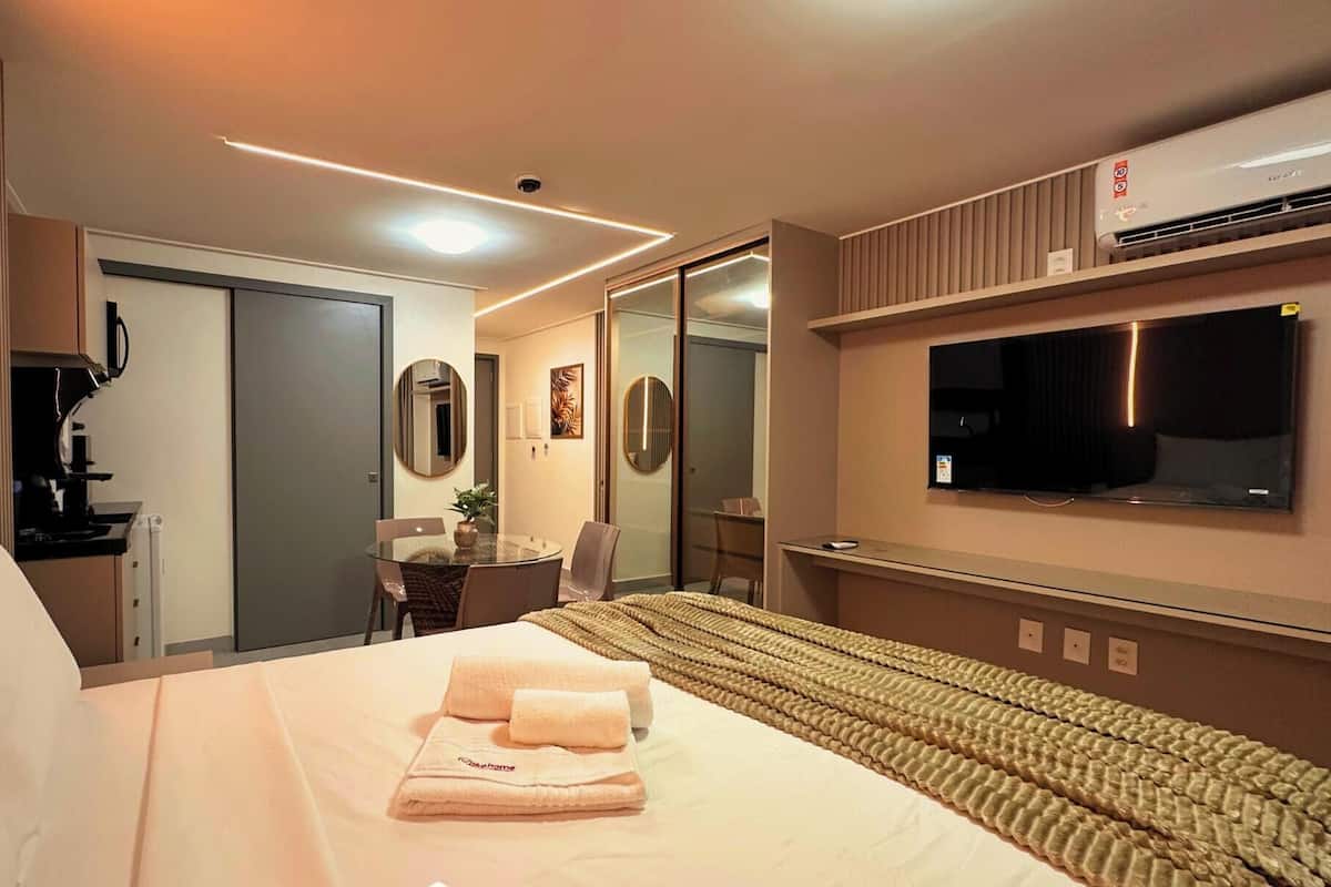 Une chambre d’hôtel avec un lit, un bureau, une chaise, une télévision et un miroir.