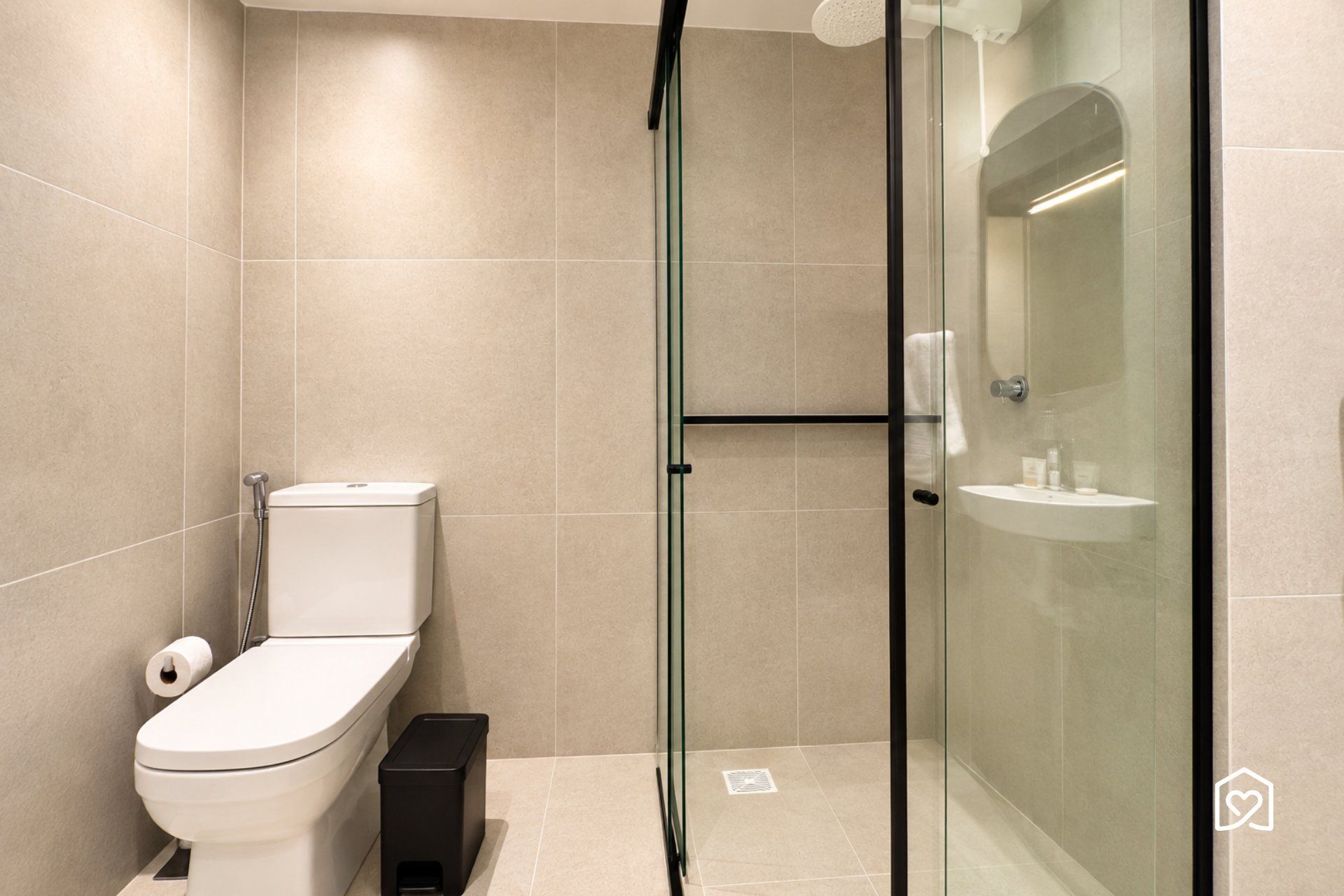 Un bany modern amb vàter, una cabina de dutxa de vidre i un lavabo.