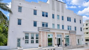 Um edifício branco com várias janelas e uma entrada central com porta de vidro.