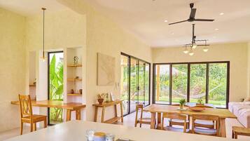A spacious room with a large dining table, wooden chairs, and a ceiling fan.