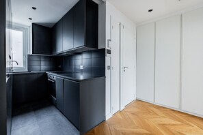Eine moderne Küche mit dunklen Schränken, einem eingebauten Backofen und einem Holzboden mit Fischgrätmuster.