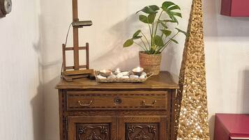 A wooden dresser with a framed painting, a potted plant, and a decorative wall piece.