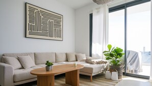 Un salón moderno con un sofá color beige, una mesa de centro de madera y un cuadro abstracto grande en la pared.