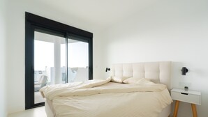 Un dormitorio moderno con una cama grande, una mesita de noche y vistas a través de un ventanal corredero.
