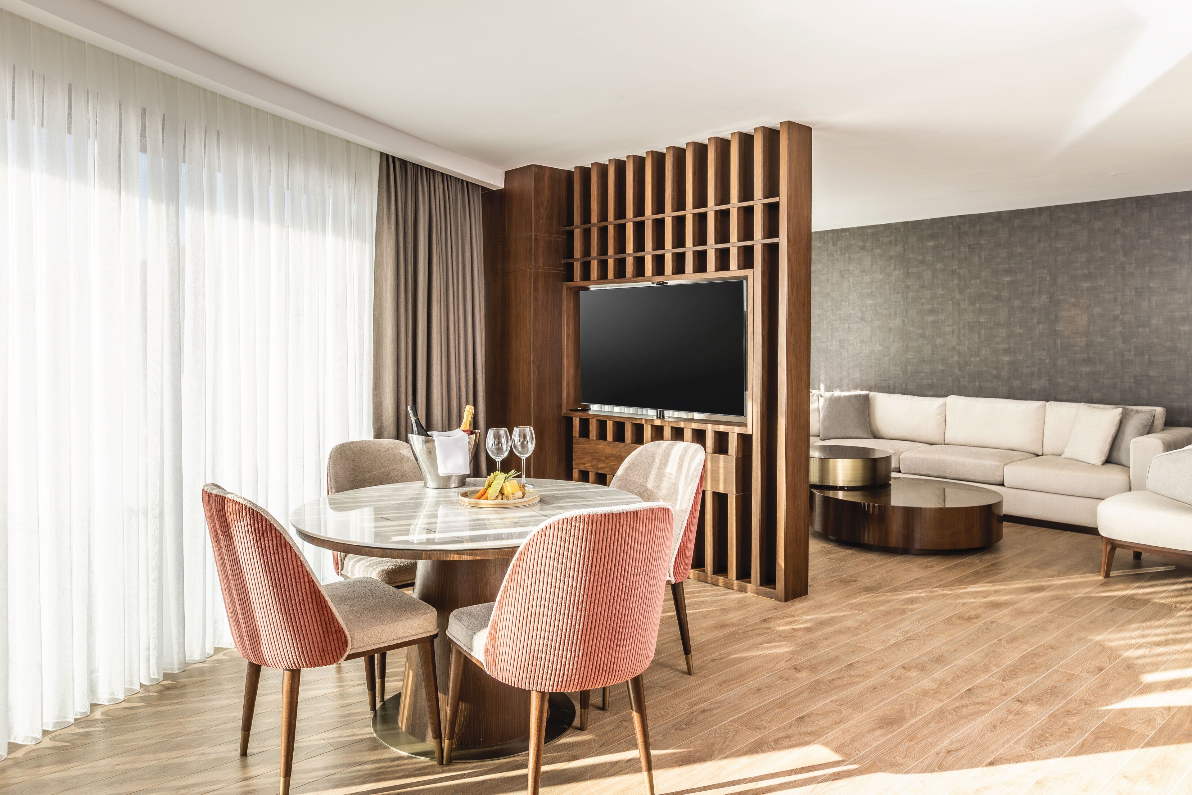 A modern living room with a dining area, a flat-screen TV, and a sofa.