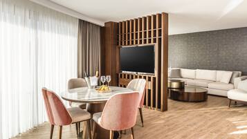 A modern living room with a dining area, a flat-screen TV, and a sofa.