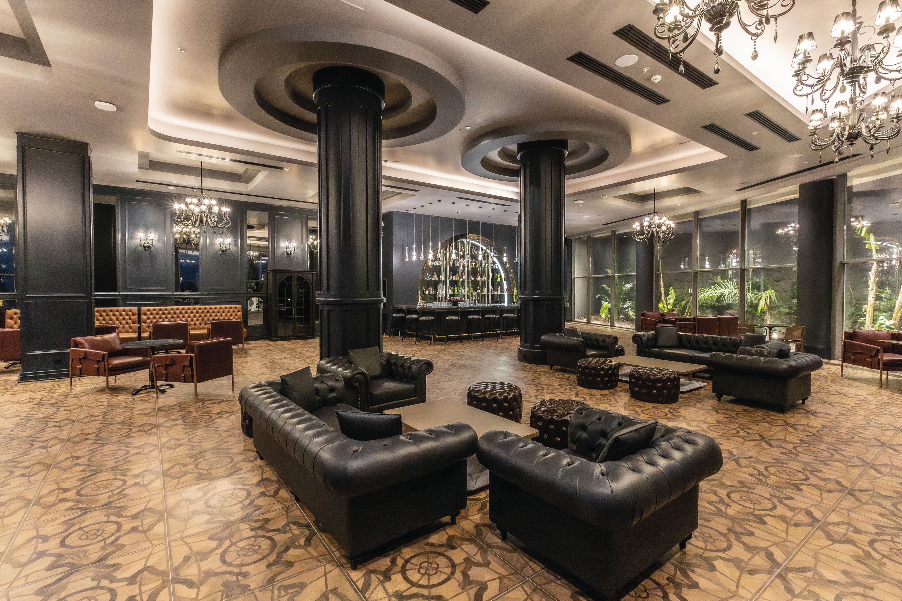 A spacious lobby with leather sofas, a bar area, and large windows.