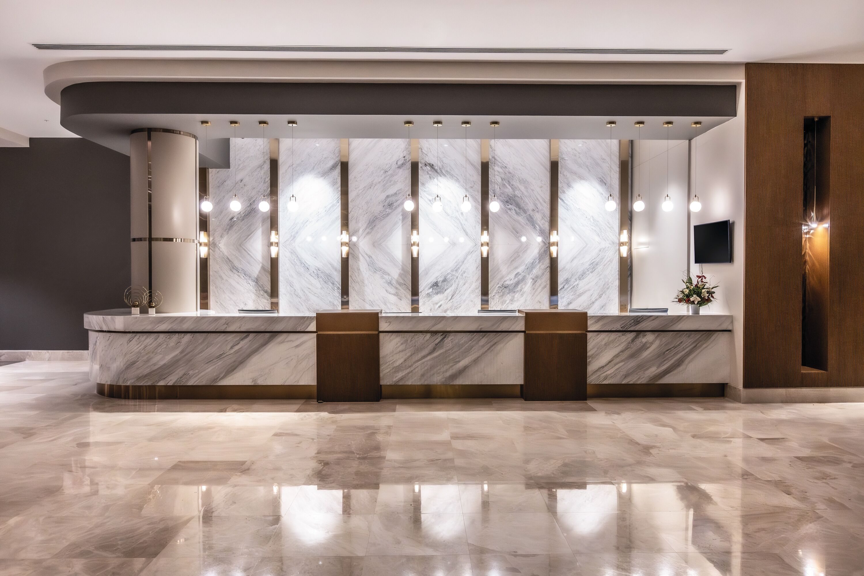 A reception area with marble counters, pendant lighting, and a flat-screen TV.