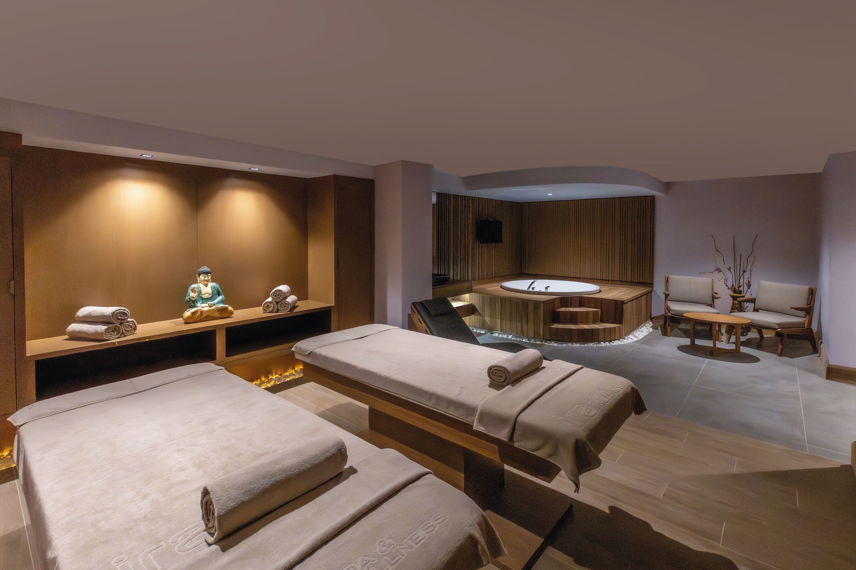 Un cuarto de spa con dos camillas de masaje, una bañera y una zona de estar.