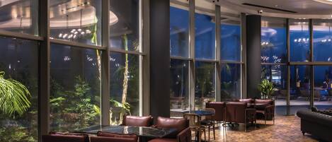 A spacious indoor area with large windows, leather seating, and a chandelier.