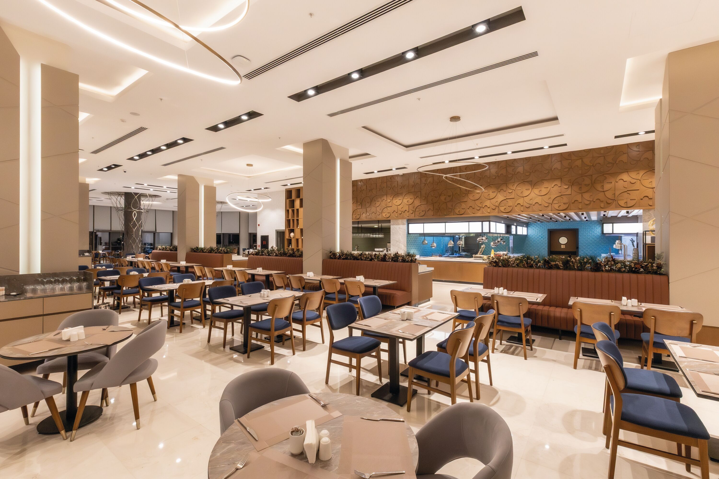 Un restaurante moderno con varias mesas y sillas, una zona de bar y una pared decorativa con un reloj.