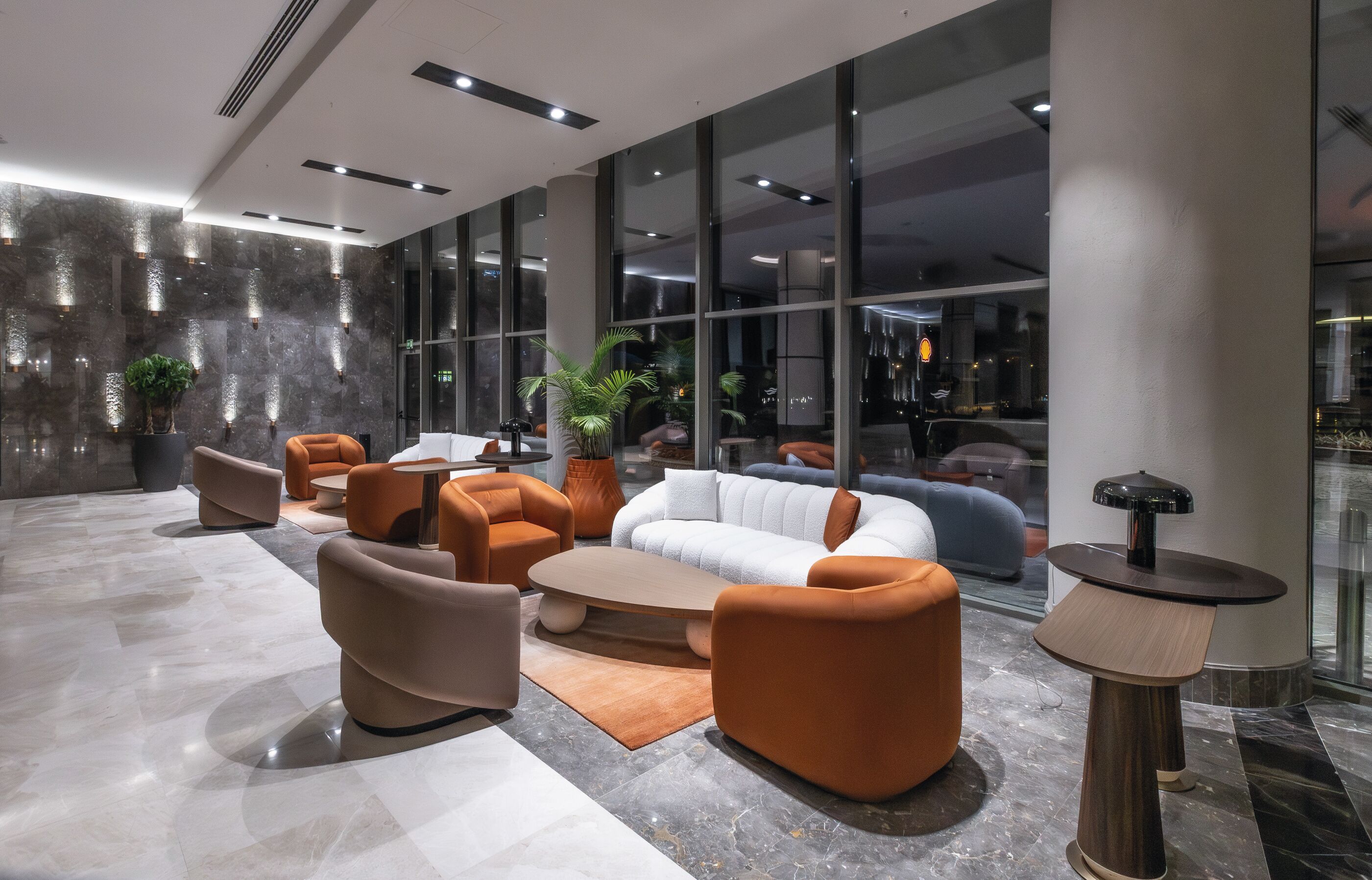 A modern lobby with seating arrangements, a coffee table, and a lamp.