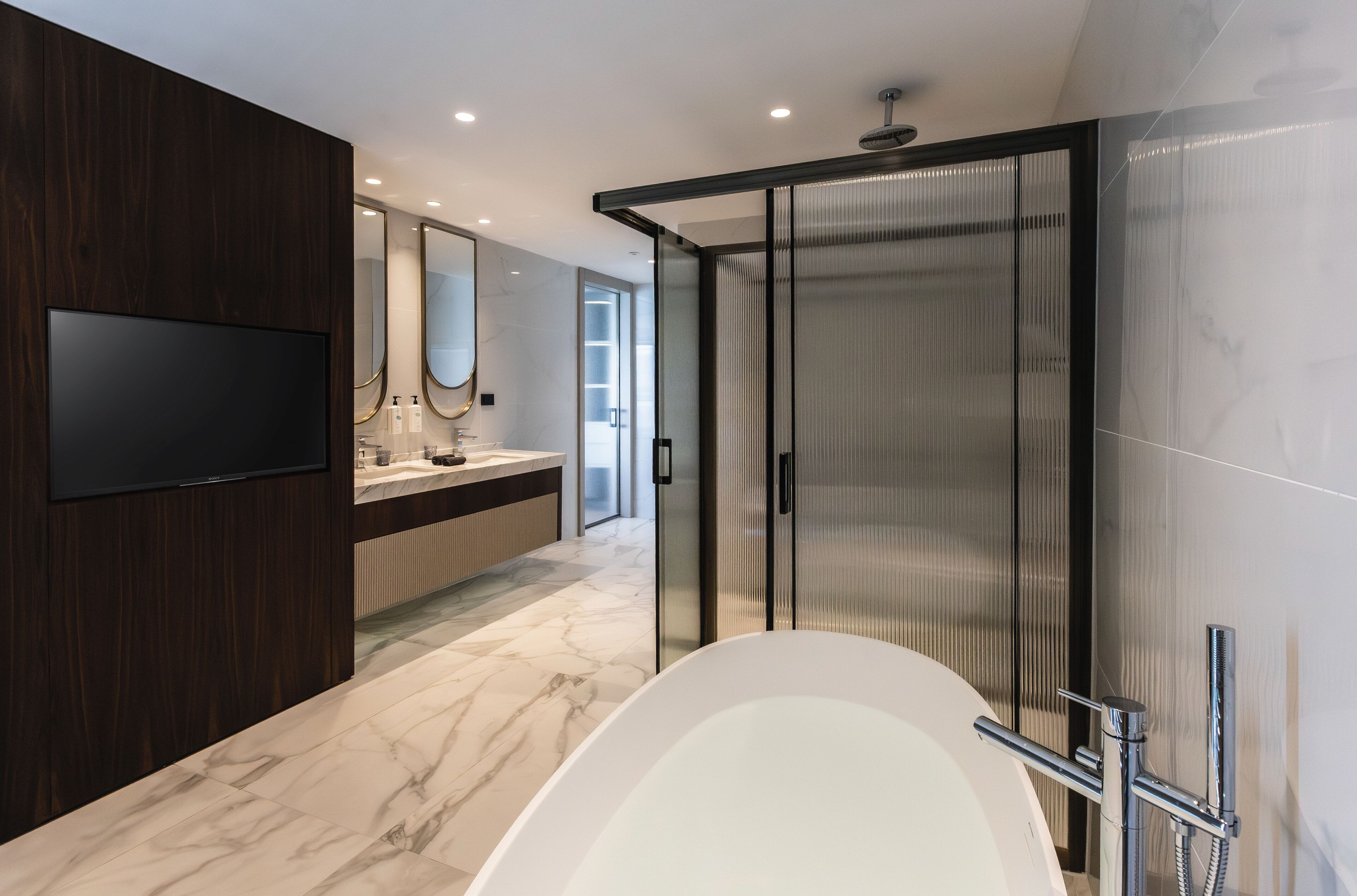 Un bagno moderno con una vasca da bagno ampia, uno specchio e un box doccia.
