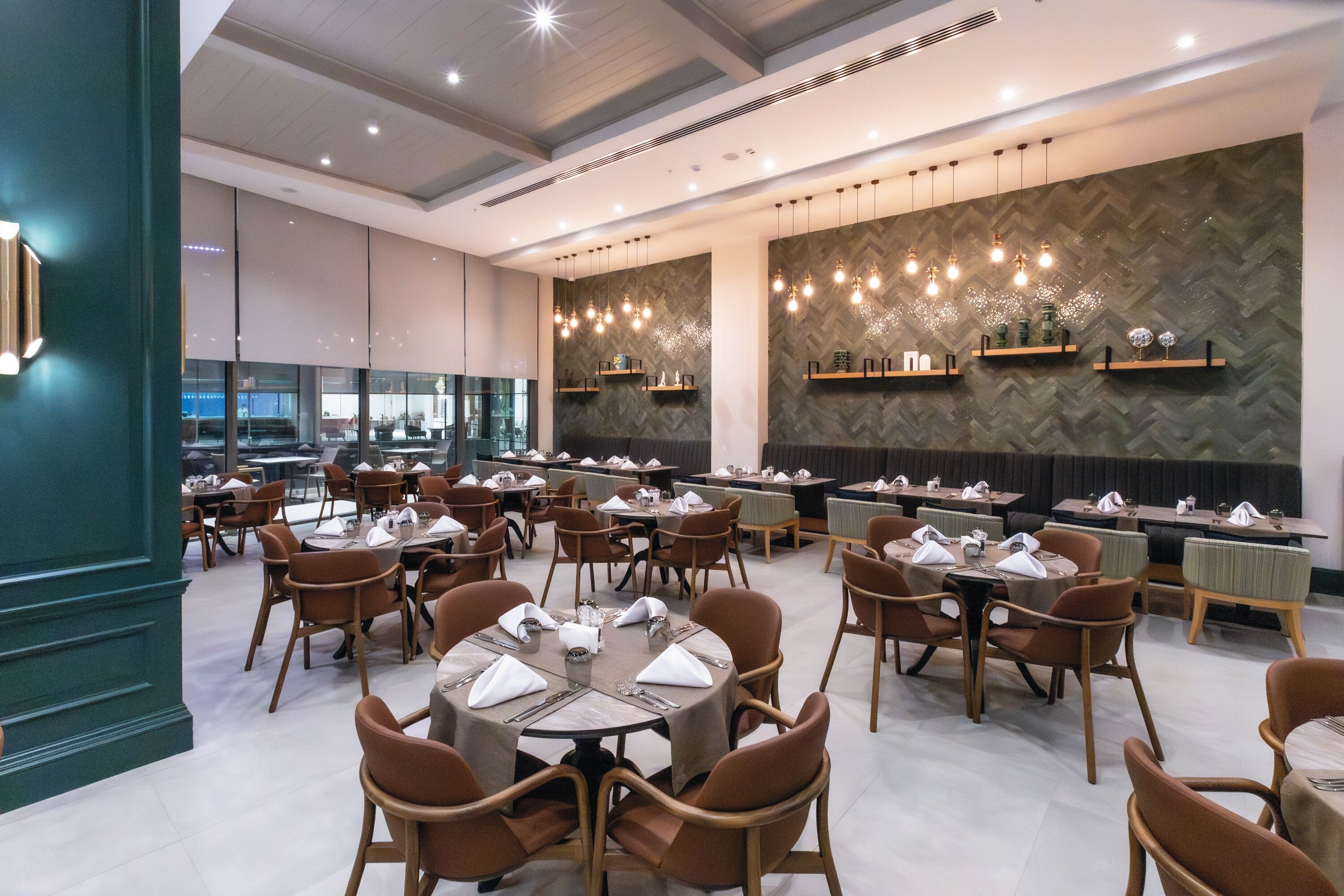 Ein geräumiges Restaurant mit hohen Decken, Pendelleuchten und modernem Interieur.