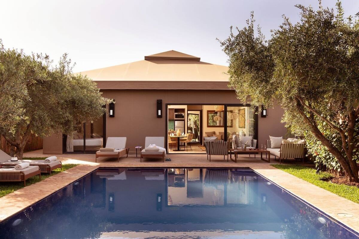 A modern outdoor pool area with lounge chairs and a dining area.