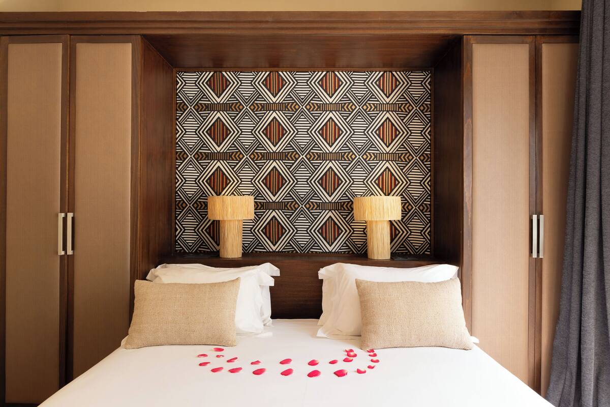 A hotel room with a large bed, two bedside lamps, and a patterned headboard.