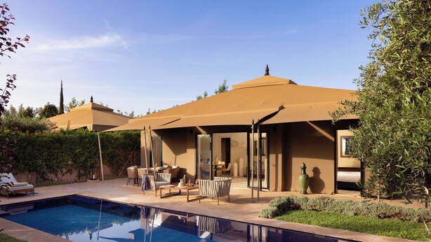 Une piscine avec un espace patio, du mobilier d’extérieur et un coin salon abrité.