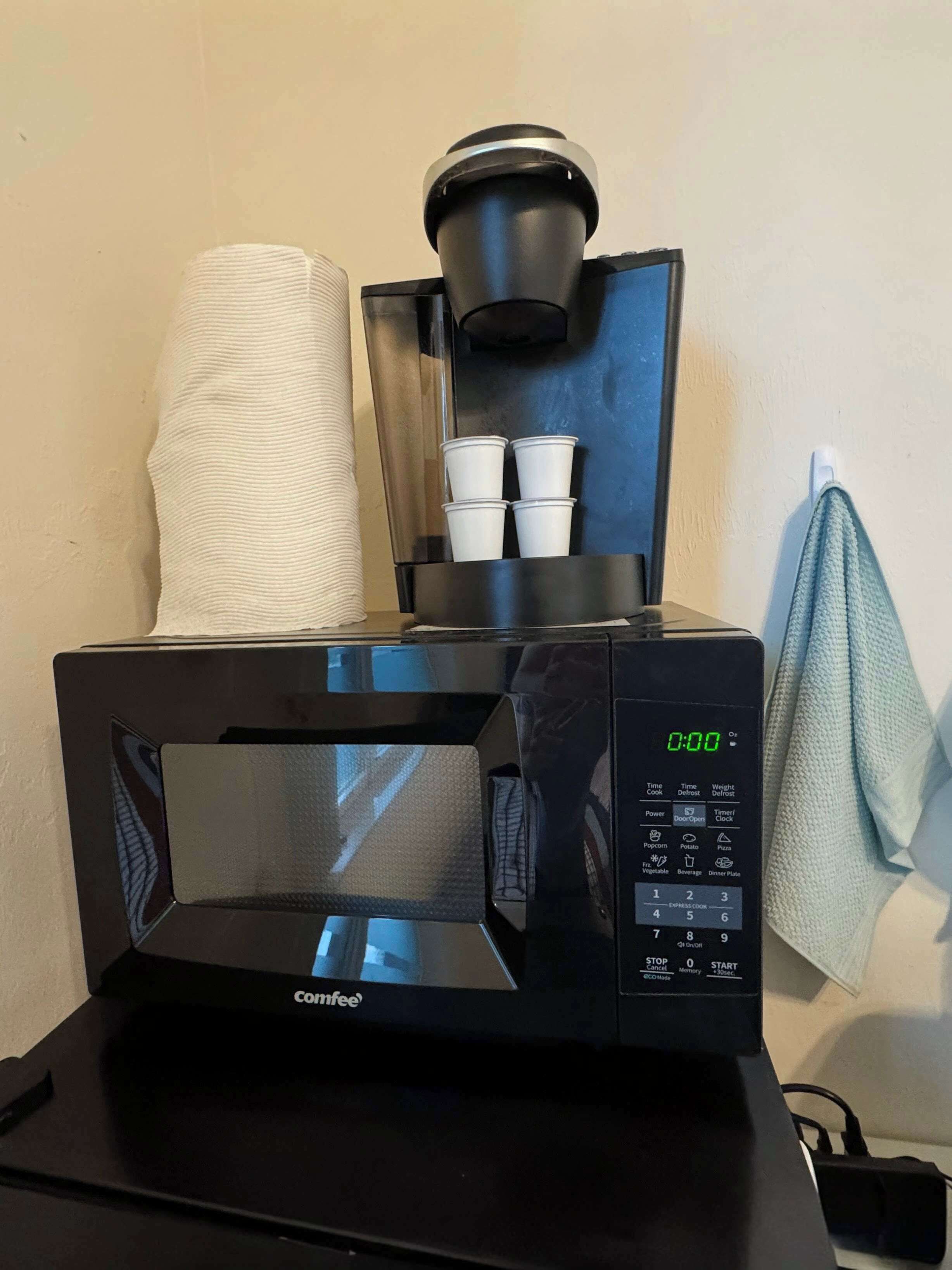 A Comfee coffee machine with a digital display, a paper towel holder, and four disposable cups.
