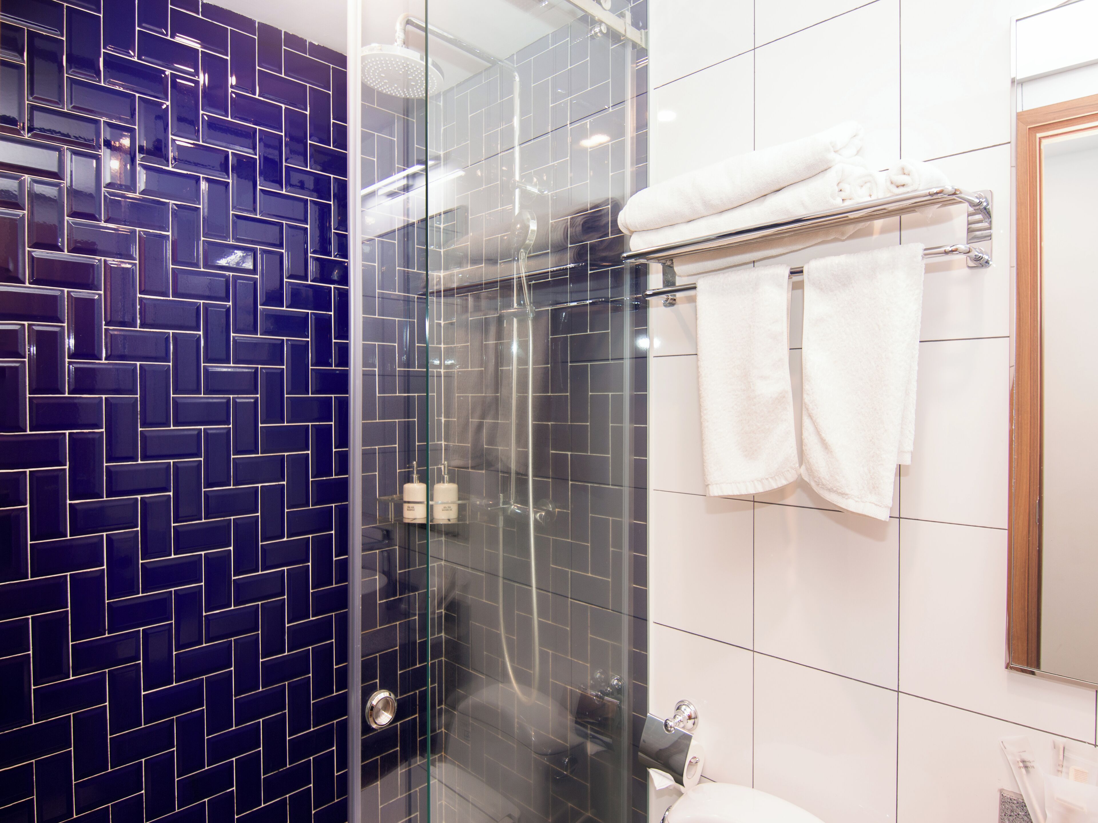 Une salle de bain avec une douche à parois de verre, un lavabo blanc et un miroir.