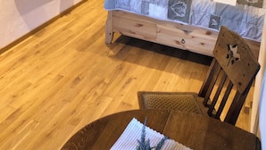Quarto com cama de madeira, televisão e janela com cortinas.