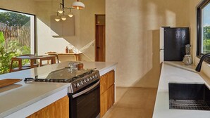 Una cocina moderna con una isla central, armarios de madera, una estufa y un amplio ventanal con vistas a zonas verdes.