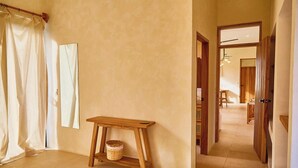 Un pasillo con un banco de madera, una cesta y una puerta que da a otra habitación.