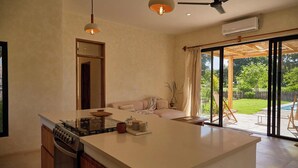 A modern kitchen with a large island, built-in oven, and a dining area with a sofa and table.
