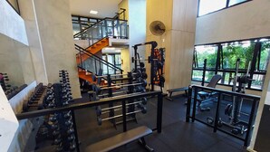 A multi-level gym with various weightlifting equipment, a staircase, and large windows with a view of greenery. - AP Estilo Resort SPA in downtown São Paulo, 24th floor, across from Brás metro station, for up to 5 people. (São Paulo)