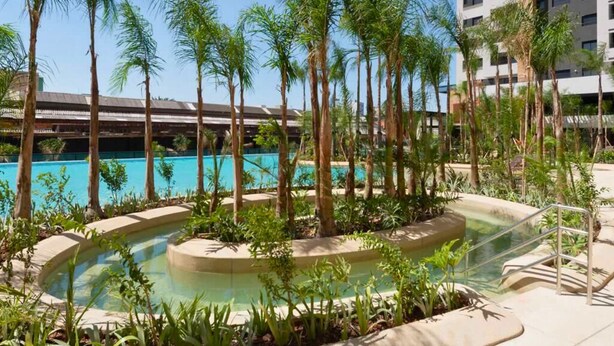 A pool area with palm trees and a building in the background. - AP Estilo Resort SPA in downtown São Paulo, 24th floor, across from Brás metro station, for up to 5 people. (São Paulo)