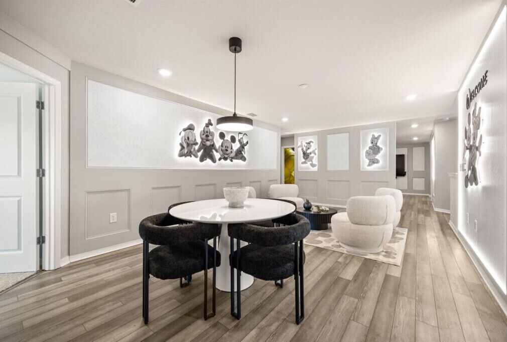 A modern dining area with a round table, black chairs, and a pendant light.