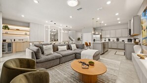 Een moderne woonkamer met een modulaire bank, een ronde salontafel, en een keuken op de achtergrond.