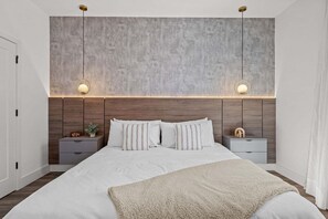 A modern bedroom with a large bed, two bedside tables, a nightstand, a wall clock, and a textured headboard. - Disney! Luxury Townhouse with Private Pool & Themed Bedrooms. Book Now! #DP68 (Orlando)