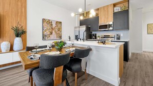 Uma cozinha moderna com uma ilha central, armários de madeira e um espaço de refeições com mesa posta para dois.