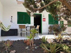 Eine Terrasse mit einer Hängematte, Stühlen und einem kleinen Garten mit Pflanzen und Steinen.