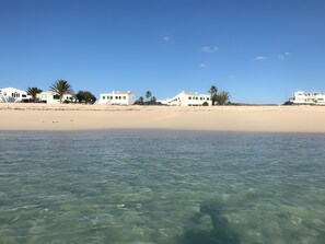 Ein Strandgrundstück mit klarem Wasser, weißen Gebäuden und Palmen.