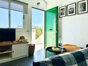 Quarto com televisão, cama, porta verde e quadros nas paredes.