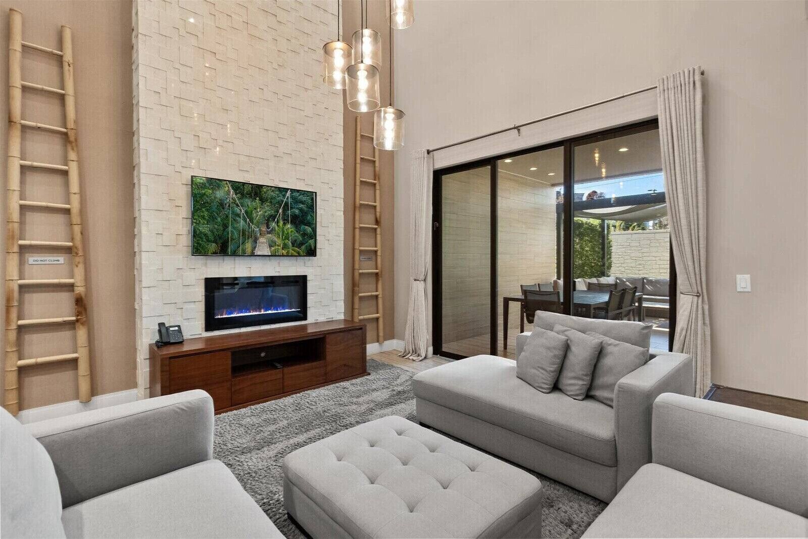 A living room with a flat-screen TV, a sofa, a coffee table, and a sliding glass door leading to an outdoor patio. - Last Minute Disney Getaway! Private Terrace & Comfortable Bedrooms. Book Now! #159485 (Orlando)