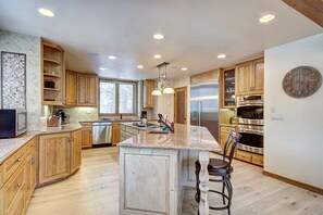 A spacious kitchen with wooden cabinets, stainless steel appliances, and a large island with bar stools.
