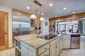 A spacious kitchen with a large island, stainless steel appliances, and wooden cabinetry.